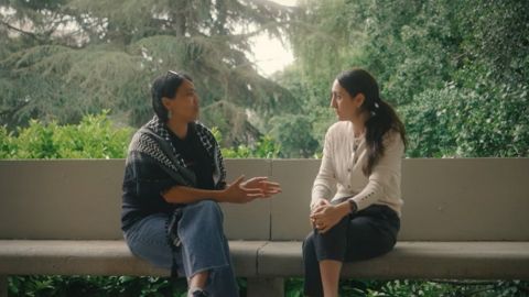 Dos mujeres hablando entre ellas sentadas en un banco.